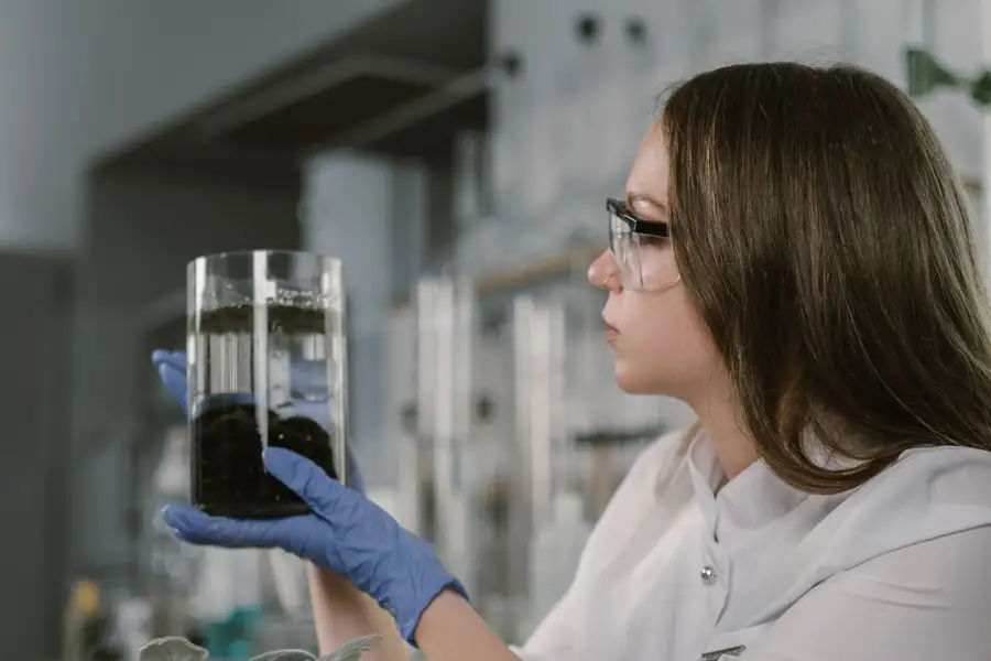 A scientist holding up a jar of soil in a lab